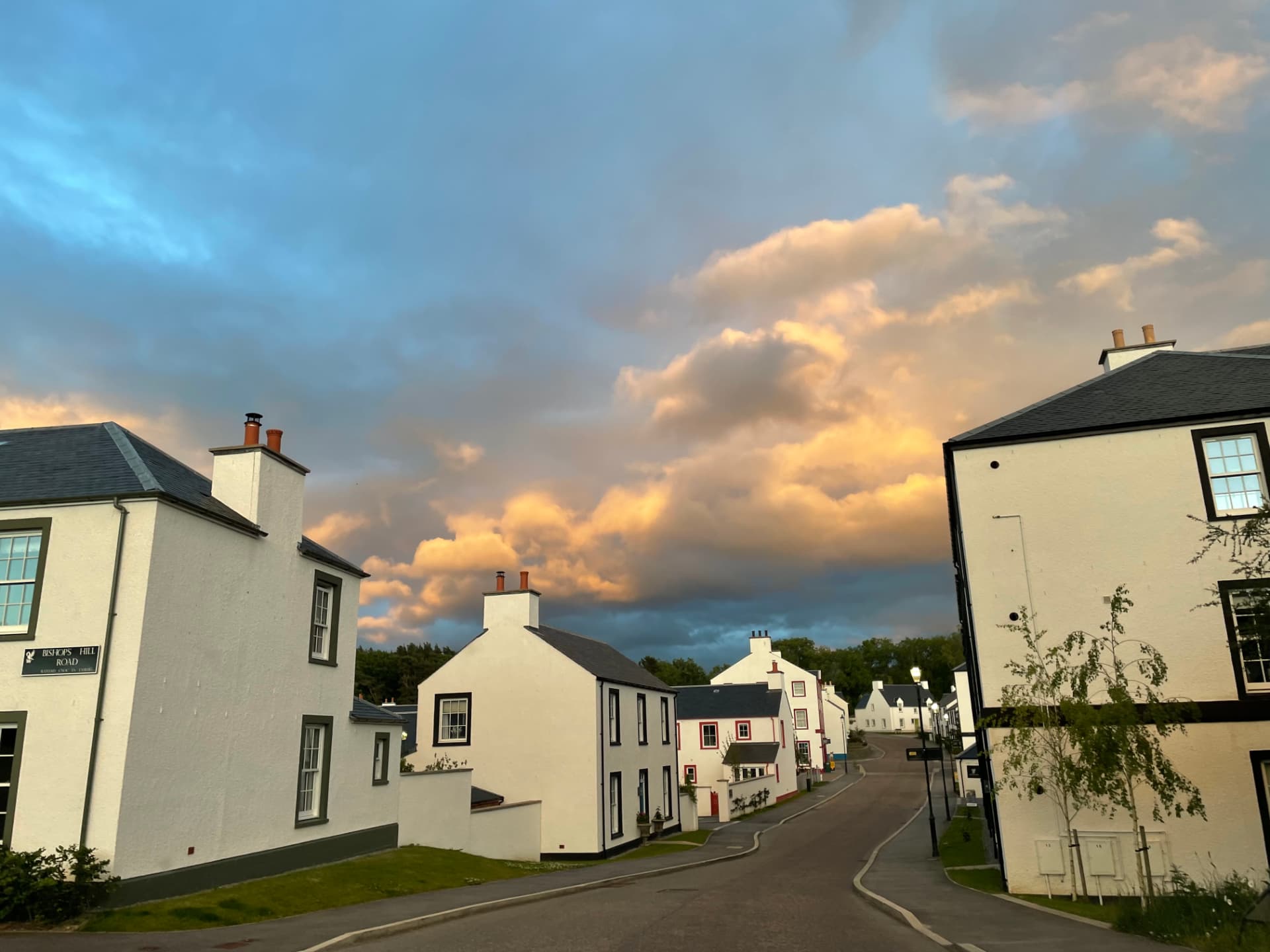 A Tornagrain street at sunset, with stone houses and young trees along the pavement